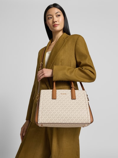 Frauenmodel trägt Handtasche aus Leder mit Logo-Muster Modell 'LAILA' von MICHAEL Michael Kors in Beige und Braun, Nahaufnahme Oberkörper. Echtes Leder, Reißverschluss, Label-Applikation, Tragehenkel und Schulterriemen, Maße siehe Kontext.