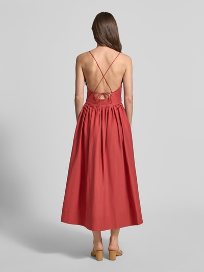Männermodel trägt Midikleid mit Eingrifftaschen Modell 'COVER' von SUNCOO PARIS, bawełniany miks, A-linia, sznurki z tyłu, kolor czerwony, widok całej sylwetki z tyłu.