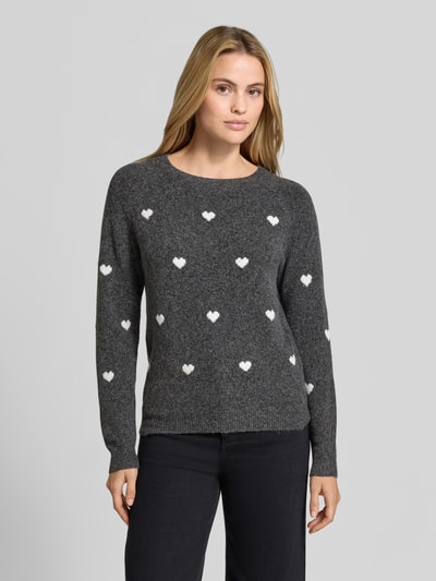Frauenmodel trägt Regular Fit Pullover mit Rundhalsausschnitt Modell 'DOFFY' von VERO MODA, dunkelgrau mit weißen Herzmustern, Ganzkörperansicht von vorne, Damen Pullover von VERO MODA.