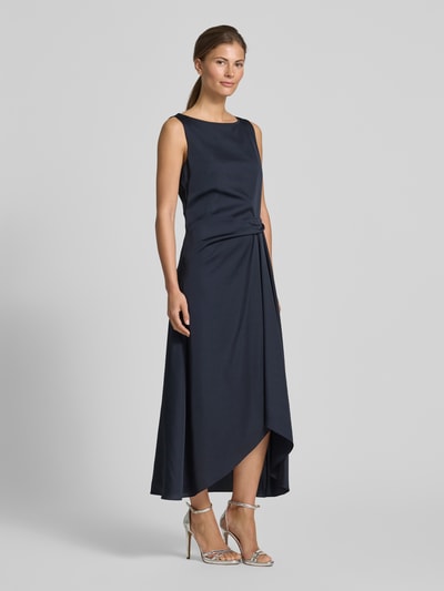 Frauenmodel trägt Cocktailkleid mit asymmetrischem Saum von Vera Mont in Dunkelblau, Taillierter Schnitt, Midikleid, U-Boot-Ausschnitt, Raffung an der Taille, Rückseitiger Reißverschluss, Rückenlänge bei Größe 36: 128 cm, Brustweite: 45 cm; Ganzkörperansicht von vorne.