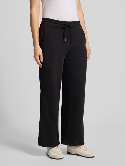 Vrouwenmodel draagt zwarte sweatpants van katoenmix, model 'HER' van PUMA met zijzakken en labelstitching, voorkantsaanzicht, Ganzkörperansicht von vorne.