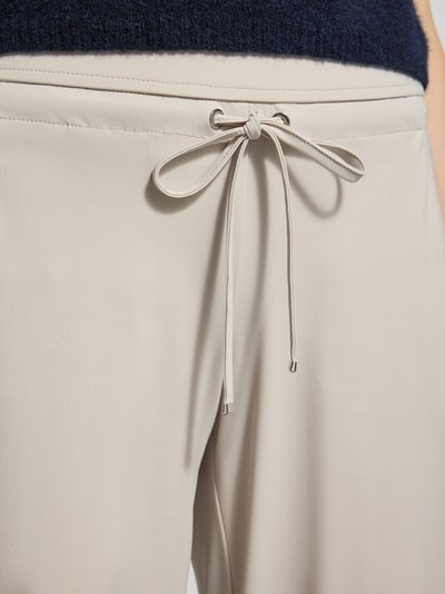 Männermodel trägt Straight Leg Jogpants aus Hightech Jersey Modell 'CANDICE' von Raffaello Rossi, elastyczny pas, wiązanie, kremowy kolor, Długość wewnętrzna nogawki 84 cm, szerokość w rozmiarze 36: 40 cm, detal pasa, zbliżenie przód.
