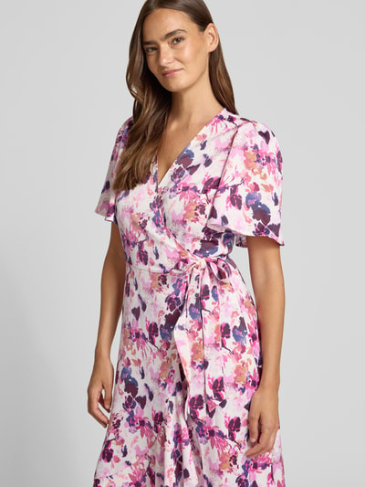Frauenmodel trägt Wickelkleid in Midilänge Modell 'Thea' von YAS, Elastischer-Material-Mix, Taillierte Passform, Kurzärmelig, V-Ausschnitt, Floraler-Print, Zierschleife, Rückenlänge 120 cm, Brustweite 46 cm, Ärmellänge 26 cm, Nahaufnahme Oberkörper.