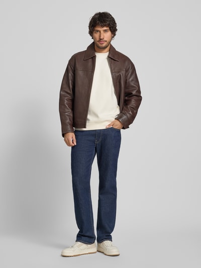 Männermodel trägt Sweatshirt mit Label-Patch Modell 'Juanfrancisco' von JOOP! Collection in Offwhite, kombiniert mit Jeans und Lederjacke, Ganzkörperansicht von vorne. Loose Fit, Baumwoll-Mix mit Stretch, Rundhalsausschnitt.