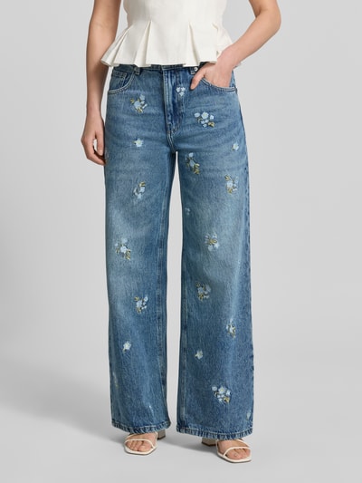 Frauenmodel trägt Wide-Fit Damen Jeans Modell 'BEVERLY' von Mango aus Reine Baumwolle mit florales Allover-Stitching, 5-Pocket-Design, Knopf-Reißverschluss, Bundweite 40 cm, Innenbeinlänge 79 cm, mittelblaue Waschung, Ganzkörperansicht von vorne.