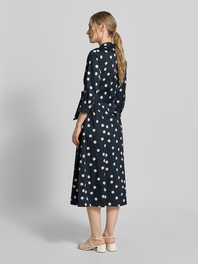 Modelka kobieca ma na sobie Regular Fit Blusenkleid aus Baumwoll-Mix od s.Oliver BLACK LABEL, granatowe, białe grochy, długość midi, pasek w talii, długie rękawy z mankietem, kieszenie, widok całej sylwetki z tyłu