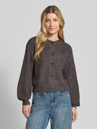 Frauenmodel trägt Loose Fit Strickjacke mit einreihiger Knopfleiste Modell 'LEA' von VERO MODA in Dunkelgrau, grobe Textur, Ganzkörperansicht von vorne.