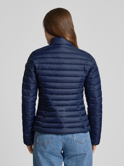 Frauenmodel trägt Slim Fit Steppjacke mit gefüttertem Stehkragen Modell 'Carly' von SAVE THE DUCK in Dunkelblau, Stepp-Optik, Ganzkörperansicht Rückansicht.