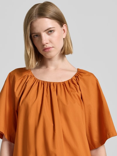 Frauenmodel trägt knielanges Kleid mit Lochstickerei und Rundhalsausschnitt von Christian Berg Woman aus Reine Baumwolle, Straight Fit, kräftiges Orange, glatte Textur, Nahaufnahme Oberkörper.
