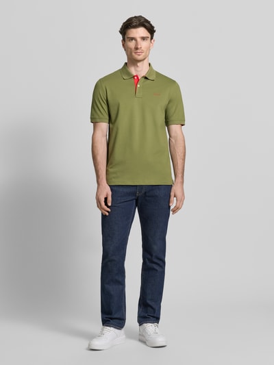 Männermodel trägt Regular Fit Poloshirt mit Logo-Stitching von Gant aus elastischem Baumwoll-Mix, grün, Polokragen, Kurzarm, Ganzkörperansicht von vorne.