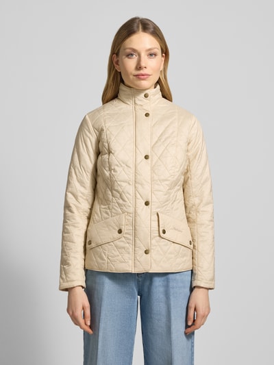 Frauenmodel trägt Regular Fit Steppjacke mit Stehkragen Modell 'FLYWEIGHT' von Barbour, unifarben beige mit Druckknöpfen und Pattentaschen, Ganzkörperansicht von vorne.