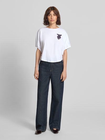 Frauenmodel trägt T-Shirt mit Motiv-Print und Kordelzug am Ärmel von Rich & Royal, reine Baumwolle, weiß, Loose Fit, Ganzkörperansicht von vorne.