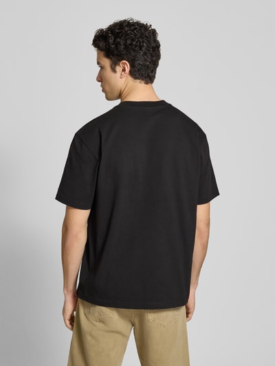 Männermodel trägt Relaxed Fit T-Shirt mit Label-Badge von G-Star Raw in Schwarz aus reiner Baumwolle, Rückenlänge 70 cm, Ganzkörperansicht Rückansicht.