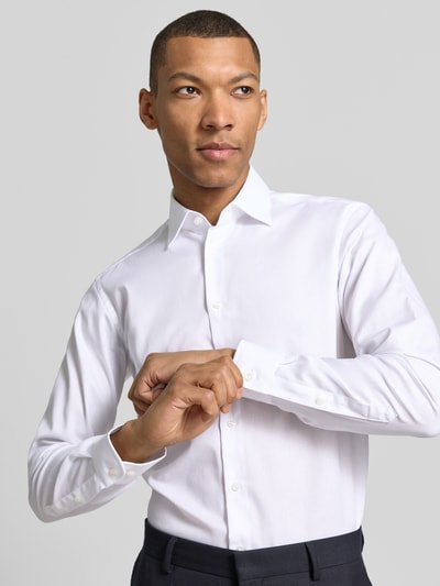 Männermodel trägt Regular Fit Business-Hemd mit Kentkragen von Christian Berg Men in Weiß, Reine Baumwolle, Nahaufnahme Oberkörper. Rückenlänge 78 cm, Schulterbreite 43 cm, Ärmellänge 65 cm, Knopfleiste und Sportmanschetten sichtbar.