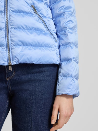 Frauenmodel trägt Taillierte Steppjacke mit Zweiwege-Reißverschluss Modell 'ANYA' von Beaumont Amsterdam in Hellblau, Nahaufnahme Oberkörper. Strukturierte Stepp-Optik, glatte, glänzende Oberfläche, sichtbare Reißverschlüsse und seitliche Eingrifftasche. Jacke tailliert geschnitten mit Kapuze und Tunnelzug, zeigt Farben und Texturen deutlich. Kontext: Damen Steppjacke, Rückenlänge 55 cm, Schulterbreite 38 cm, Brustweite 48 cm, Ärmellänge 61 cm.