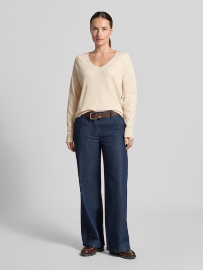 Frauenmodel trägt Strickpullover aus Viskose-Mix Modell 'FREYJA' von Oui in Beige mit V-Ausschnitt, gerade Passform, Ganzkörperansicht von vorne.