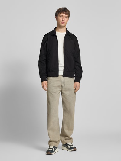 Männermodel trägt Jacke mit Stehkragen und Reißverschluss von G-Star Raw aus Baumwoll-Mix in Schwarz, Regular Fit, Ganzkörperansicht von vorne.