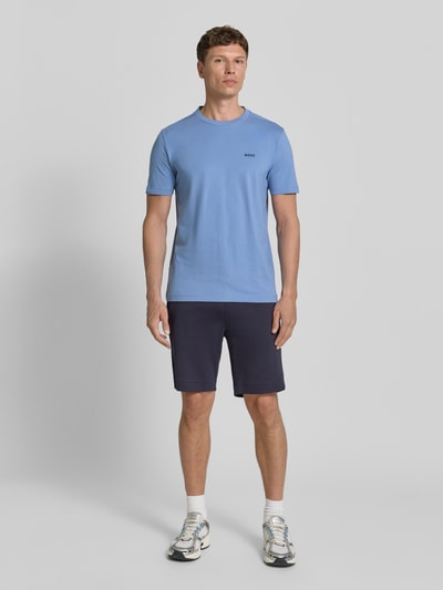 Männermodel trägt Regular Fit T-Shirt aus Baumwoll-Mix Modell 'TEE' von BOSS Green in Hellblau, Label Print, Ganzkörperansicht von vorne.