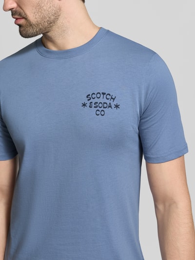 Männermodel trägt T-Shirt mit Rundhalsausschnitt von Scotch & Soda in Blau, Reine Baumwolle, Regular-Fit, Label-Print, Nahaufnahme Oberkörper.