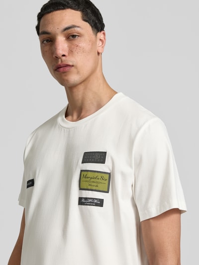 Männermodel trägt Relaxed Fit T-Shirt mit Logo-Patch von MM6 Maison Margiela aus reiner Baumwolle, Weiß, Rundhalsausschnitt, Nahaufnahme Oberkörper.