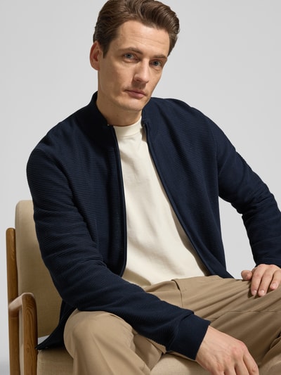 Męski model nosi Regular Fit Cardigan mit Stehkragen von OLYMP Level Five z bawełny, imitacja dzianiny, zamek błyskawiczny, krój regular fit, długość tyłu 68 cm, długość rękawów 67 cm, elastyczne wykończenia, granatowy, imitacja dzianiny, widok z przodu, zbliżenie na górną część ciała.