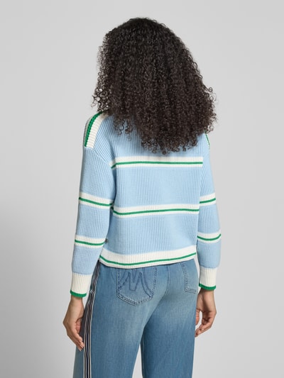 Kobiece modelka nosi Strickpullover mit U-Boot-Ausschnitt od Marc Cain w odcieniach niebieskiego i bieli, krój regular fit, mieszanka bawełny, prążkowana tekstura, luźne ramiona, widok całej sylwetki od tyłu.