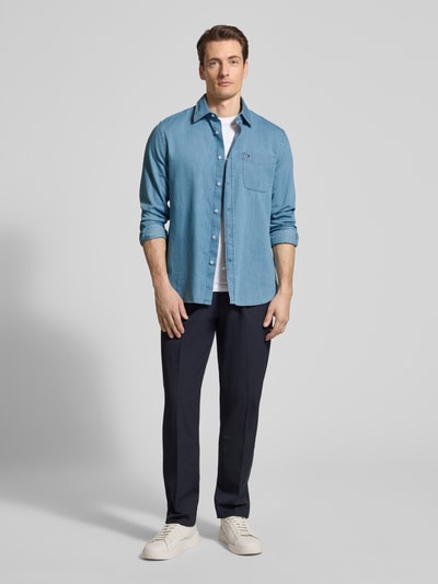 Männermodel trägt Regular Fit Jeanshemd aus reiner Baumwolle von Tommy Hilfiger in Denim-Optik, Haifischkragen, Ganzkörperansicht von vorne.