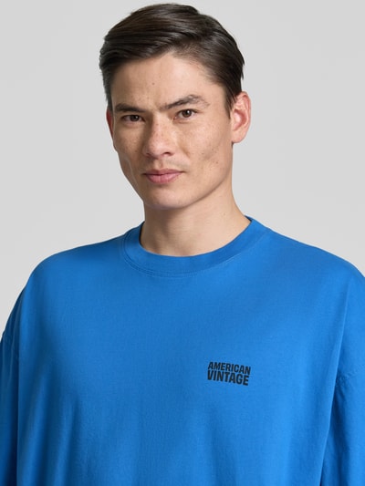 Männermodel trägt Herren T-Shirt mit Logo-Print Modell 'GIXY' von American Vintage in Blau aus Reine Baumwolle, Nahaufnahme Oberkörper.