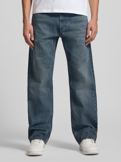 Männermodel trägt Straight Fit Jeans im 5-Pocket-Design Modell 'Ash' von Calvin Klein Jeans aus reiner Baumwolle, blauer Denim, Ganzkörperansicht von vorne.