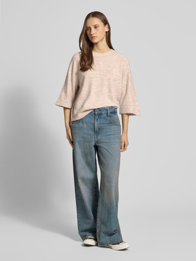 Frauenmodel trägt Oversized Strickpullover mit 3/4-Arm Modell 'SIMONI' von ONLY in Unifarben Melange-Strickoptik, ganzkörperansicht von vorne.