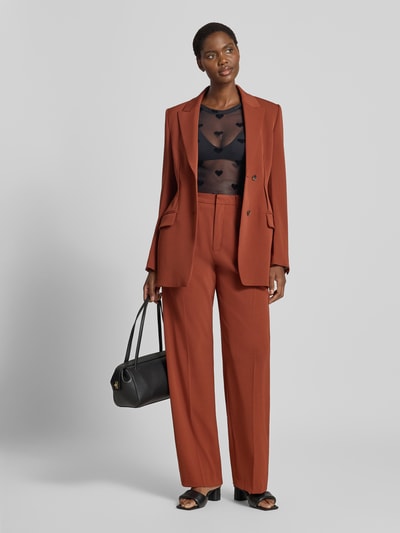Frauenmodel trägt Slim Fit Langarmshirt mit Rundhalsausschnitt Modell 'LOVA' von VERO MODA in Schwarz unter braunem Hosenanzug, Ganzkörperansicht von vorne.