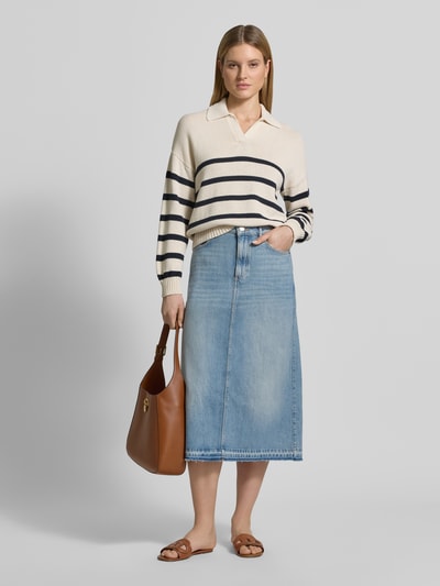 Kobiece modelka nosi spódnica jeansowa „Ausgestellter Jeansrock aus reiner Baumwolle” od Marc O'Polo z bawełnianego denimu w długości midi, rozkloszowany krój, 5 kieszeni, nity, naszywka z logo, szlufki na pasek, otwarta krawędź; jasnoniebieskie kolory i gładka tekstura; widok całej sylwetki z przodu.