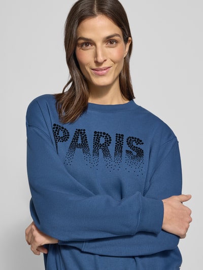 Frauenmodel trägt Regular Fit Sweatshirt aus Baumwoll-Mix von Tom Tailor Denim, blau, Schriftzug-Print, Crew Neck, Nahaufnahme Oberkörper.