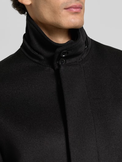 Männermodel trägt schwarzen Regular Fit Mantel aus reiner Viskose Modell 'Aleric' von Tiger of Sweden, Nahaufnahme Oberkörper.