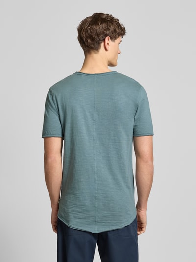 Männermodel trägt Regular Fit T-Shirt aus reiner Baumwolle Modell 'BENNE LONGY' von Only & Sons, unifarben, Rollsaum, Ganzkörperansicht Rückansicht.