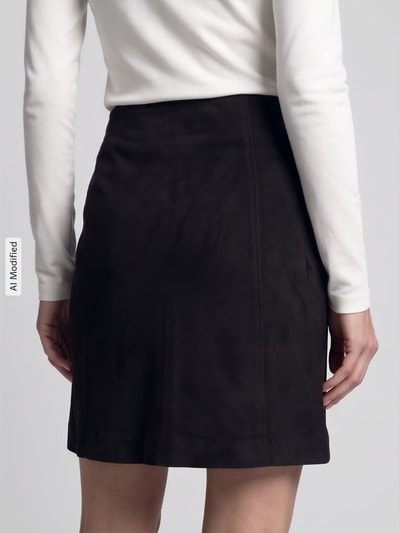 Frauenmodel trägt Ausgestellter Mini-Rock mit Teilungsnähten Modell 'DONNAHAZEL' von VERO MODA in Schwarz, glatte Struktur, Ganzkörperansicht Rückansicht, KI-modifiziertes Bild.