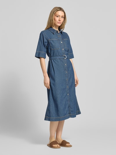 Frauenmodel trägt Fit and Flare Jeanskleid aus reiner Baumwolle von Tommy Hilfiger in mittlerem Blauton mit Knopfleiste, Gürtel und kurzen Ärmeln, Denim-Optik, Midi-Länge, Logo-Stitching, Brust- und Eingrifftaschen, Ganzkörperansicht von vorne.