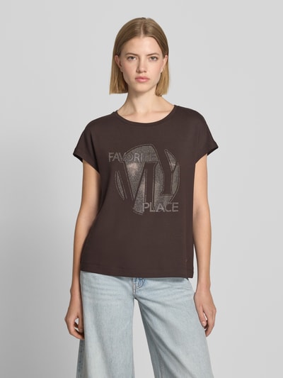 Frauenmodel trägt T-Shirt aus Viskose-Mix mit Ziersteinbesatz von monari in Dunkelbraun, Rundhalsausschnitt, Regular Fit, Ganzkörperansicht von vorne.