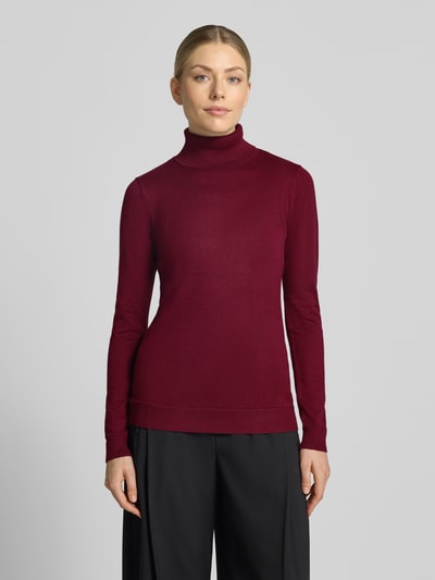 Frauenmodel trägt Slim Fit Strickpullover aus Viskose-Mix Modell 'IHLULS' von ICHI in dunklem Rot, feine Textur, Ganzkörperansicht von vorne. Damenpullover mit Rollkragen und elastischen Abschlüssen, Rückenlänge 61 cm, Ärmellänge 66 cm.