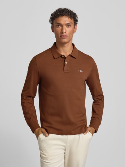 Männermodel trägt Regular Fit Poloshirt mit Label-Stitching von Gant in Braun, Reine Baumwolle, Polokragen, Knopfleiste, Ganzkörperansicht von vorne. Rückenlänge bei Größe M: 68 cm.
