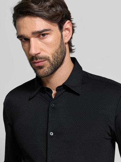 Männermodel trägt Slim Fit Business Hemd mit Kentkragen Modell 'ROAN' von BOSS, unifarbenes Schwarz, Stretch-Material, Nahaufnahme Oberkörper.