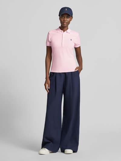 Frauenmodel trägt Slim Fit Poloshirt aus Baumwoll-Mix von Polo Ralph Lauren in Rosa, kombiniert mit weiter Hose, Ganzkörperansicht von vorne. Damen Poloshirt von Polo Ralph Lauren.