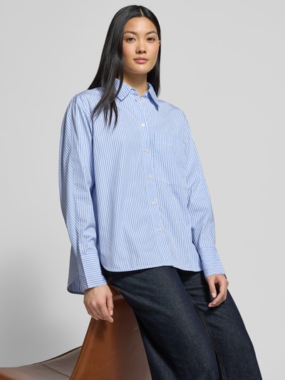 Frauenmodel trägt Regular Fit Hemdbluse aus reiner Baumwolle von Marc O'Polo mit blau-weißem Allover-Streifenmuster, Knopfleiste und Manschetten, Ganzkörperansicht von vorne.
