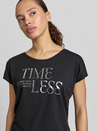 Frauenmodel trägt T-Shirt mit Statement-Print und Rundhalsausschnitt von Christian Berg Woman aus Baumwoll-Viskose-Mix, Regular-Fit, schwarze Farbe, glatte Textur, Rückenlänge bei Größe S 66 cm, Nahaufnahme Oberkörper.
