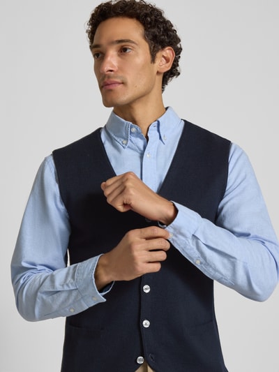 Männermodel trägt Slim Fit Weste aus Woll-Mix von Christian Berg Men in Dunkelblau mit Knopfleiste und V-Ausschnitt, Nahaufnahme Oberkörper, Strick-Optik.