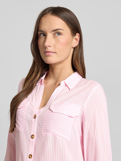 Vrouwenmodel draagt Relaxed Fit Hemdbluse aus reiner Viskose Modell 'BUMPY' van Vero Moda, roze-wit gestreept, borstzakken, detailopname bovenlichaam.