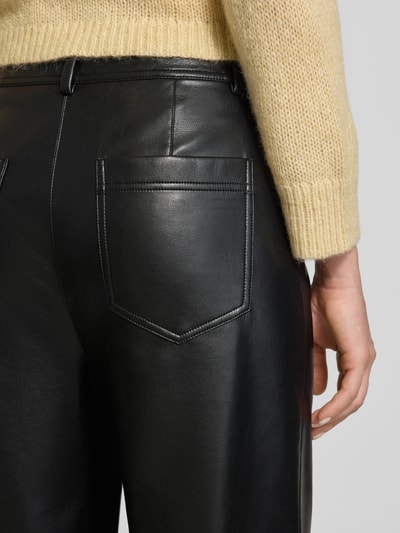 Frauenmodel trägt Straight Fit Hose mit Eingrifftaschen von Marc Cain in schwarzer Leder-Optik, sichtbare Gesäßtasche, Nahaufnahme Rückansicht.