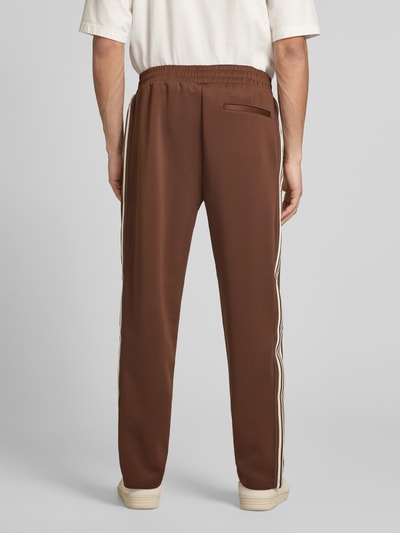 Männermodel trägt Regular Fit Sweatpants mit elastischem Bund Modell 'RIBER' von Only & Sons, bruin, uni, contraststrepen, fijne webstructuur, zijzakken, ganzkörperansicht rückansicht.