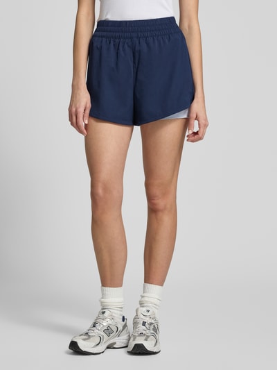 Frauenmodel trägt Regular Fit Sport-Shorts mit Logo-Applikation von Lacoste Sport in Dunkelblau, Piqué-Stretch, unifarben, Ganzkörperansicht von vorne.