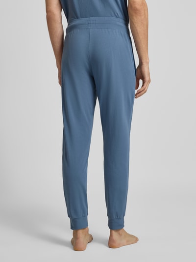 Männermodel trägt Regular Fit Sweathose aus Baumwoll-Mix Modell 'LAZE' von HUGO in Blau mit elastischem Bund, Sweatstruktur, Ganzkörperansicht Rückansicht.